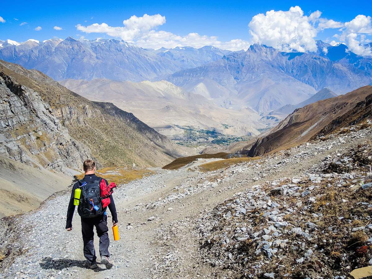 people man carrying backpack walking on mountain at daytime person