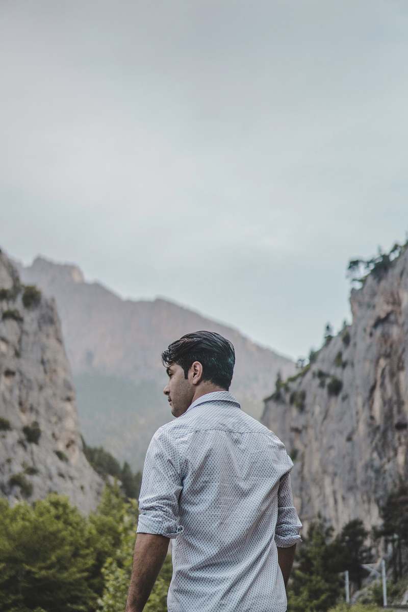 people man facing rock formation at daytime person