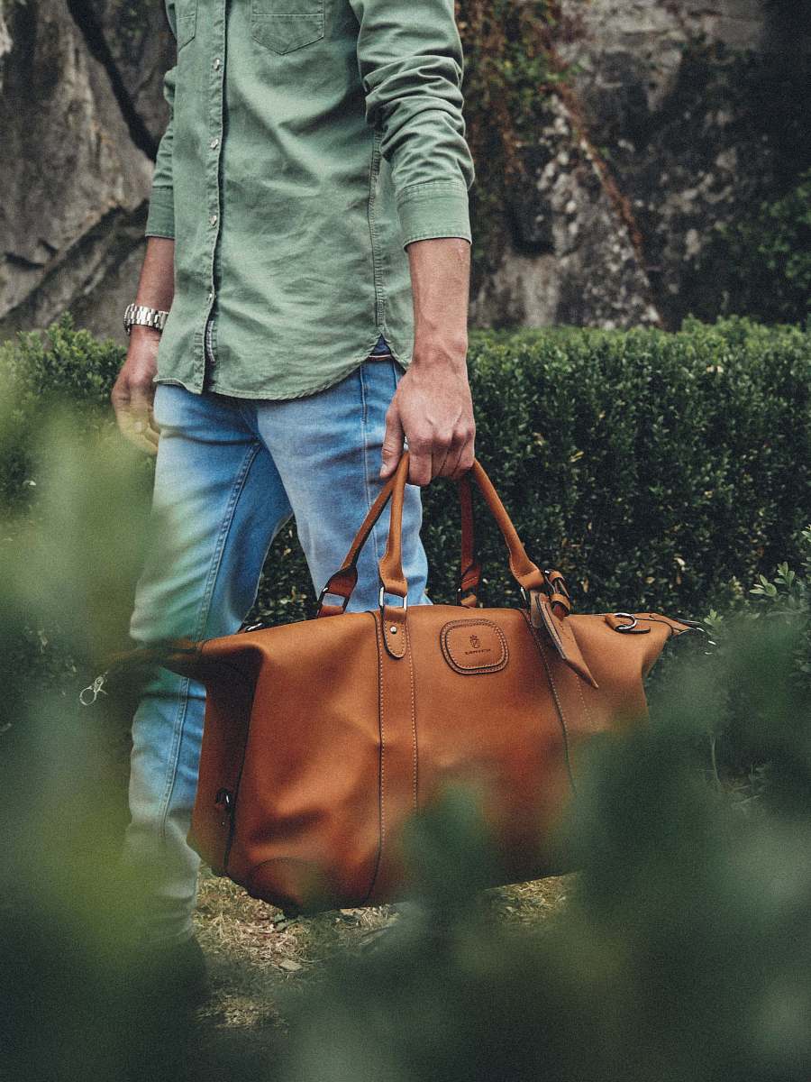 person man holding bag near grass people