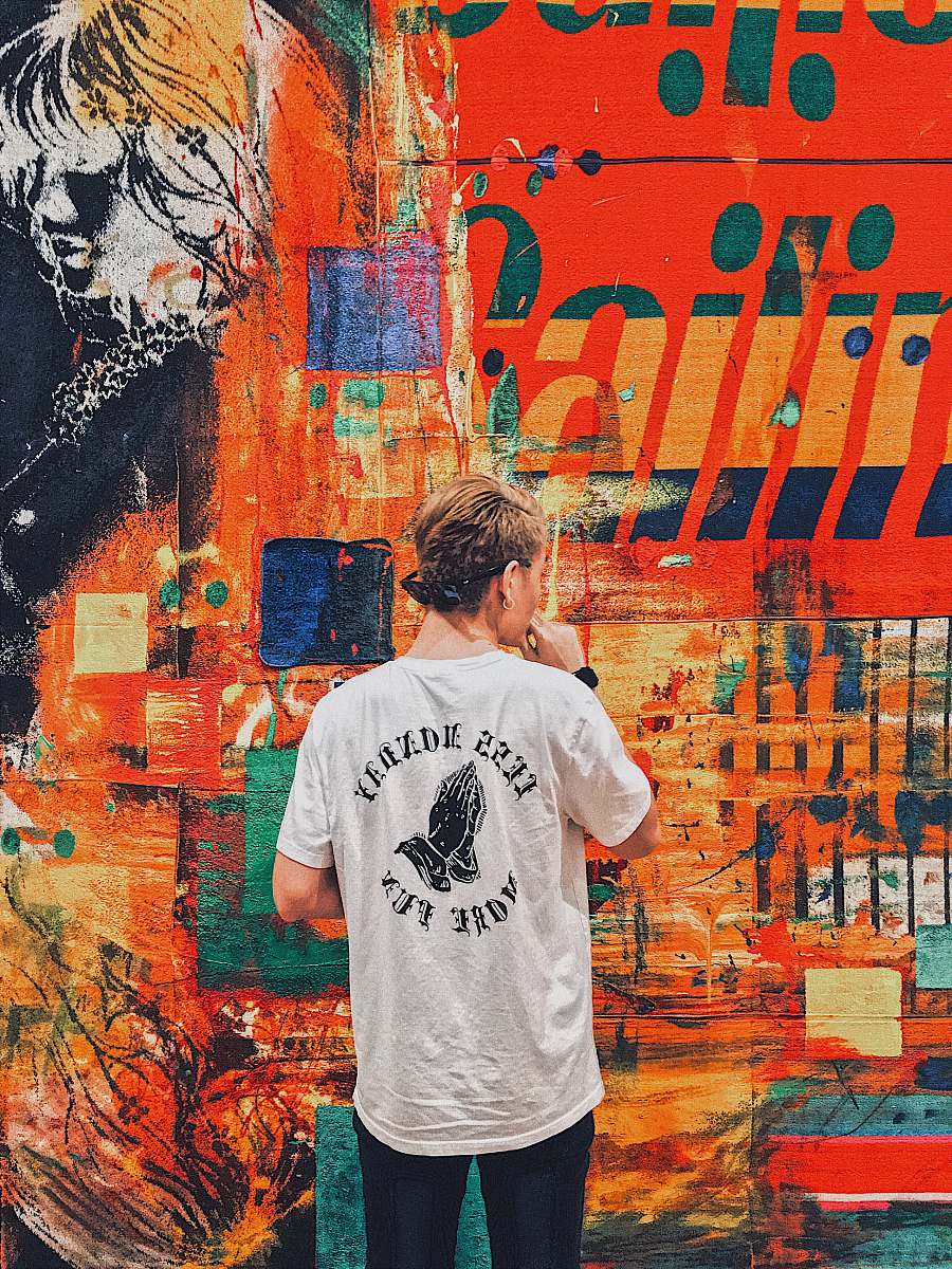 people man holding his chin facing multicolored painted wall person