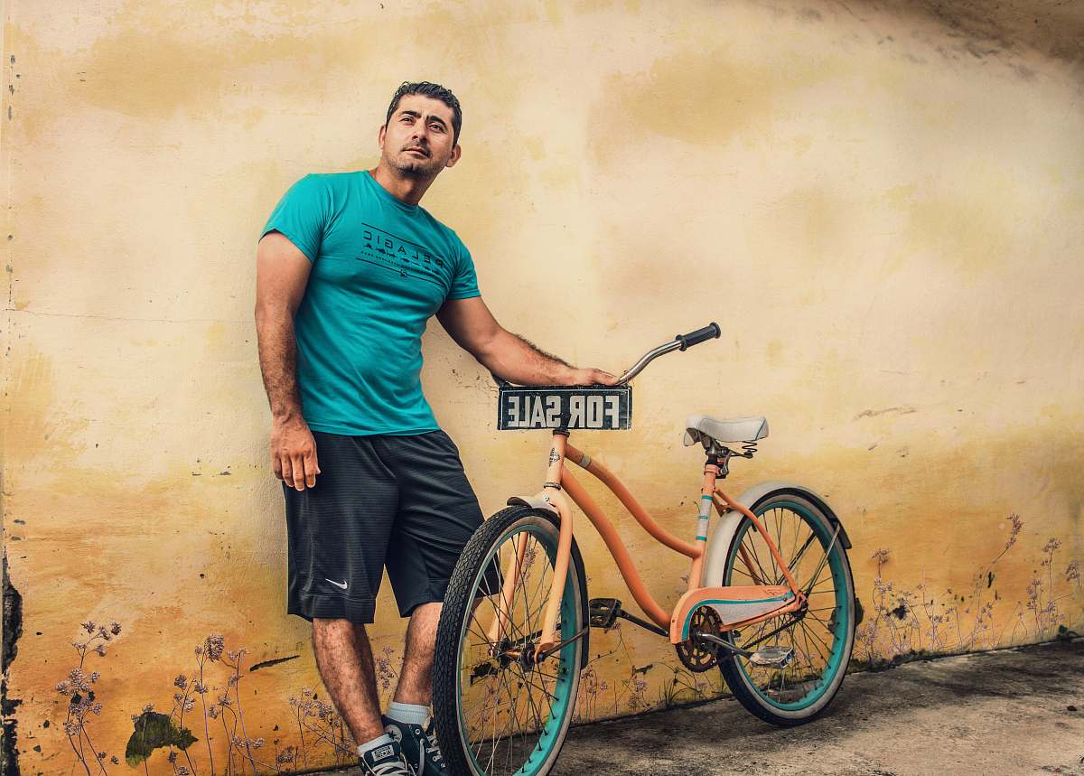 bicycle man holding orange beach cruiser bike