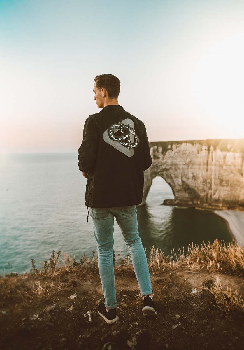 people man in black and white blazer standing near cliff person