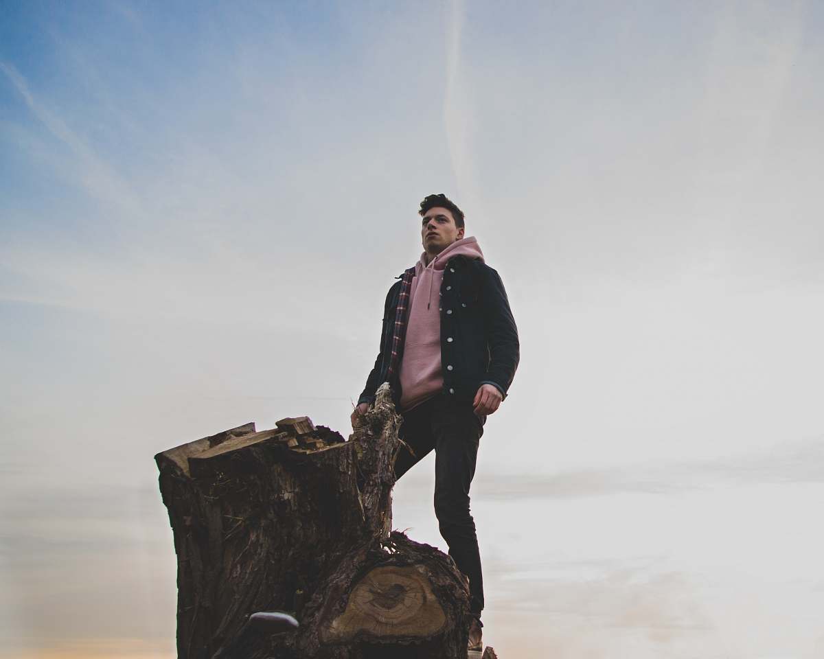 people man in black jacket and pink pullover hoodie standing on tree log person