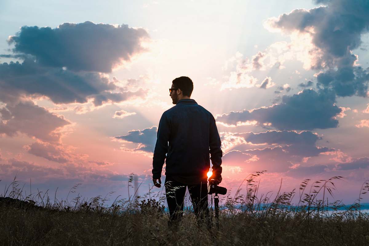 people man in black long-sleeved shirt holding DSLR camera standing on grass person
