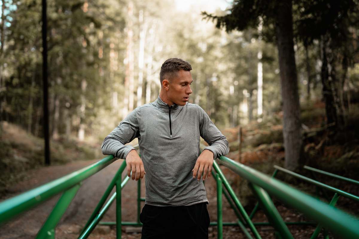 people man in gray sweater standing in middle of two green steel frames person