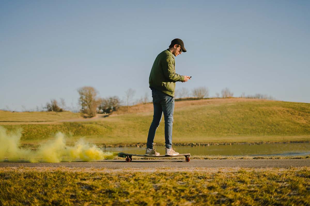 people man in green jacket and blue jeans on skateboard person