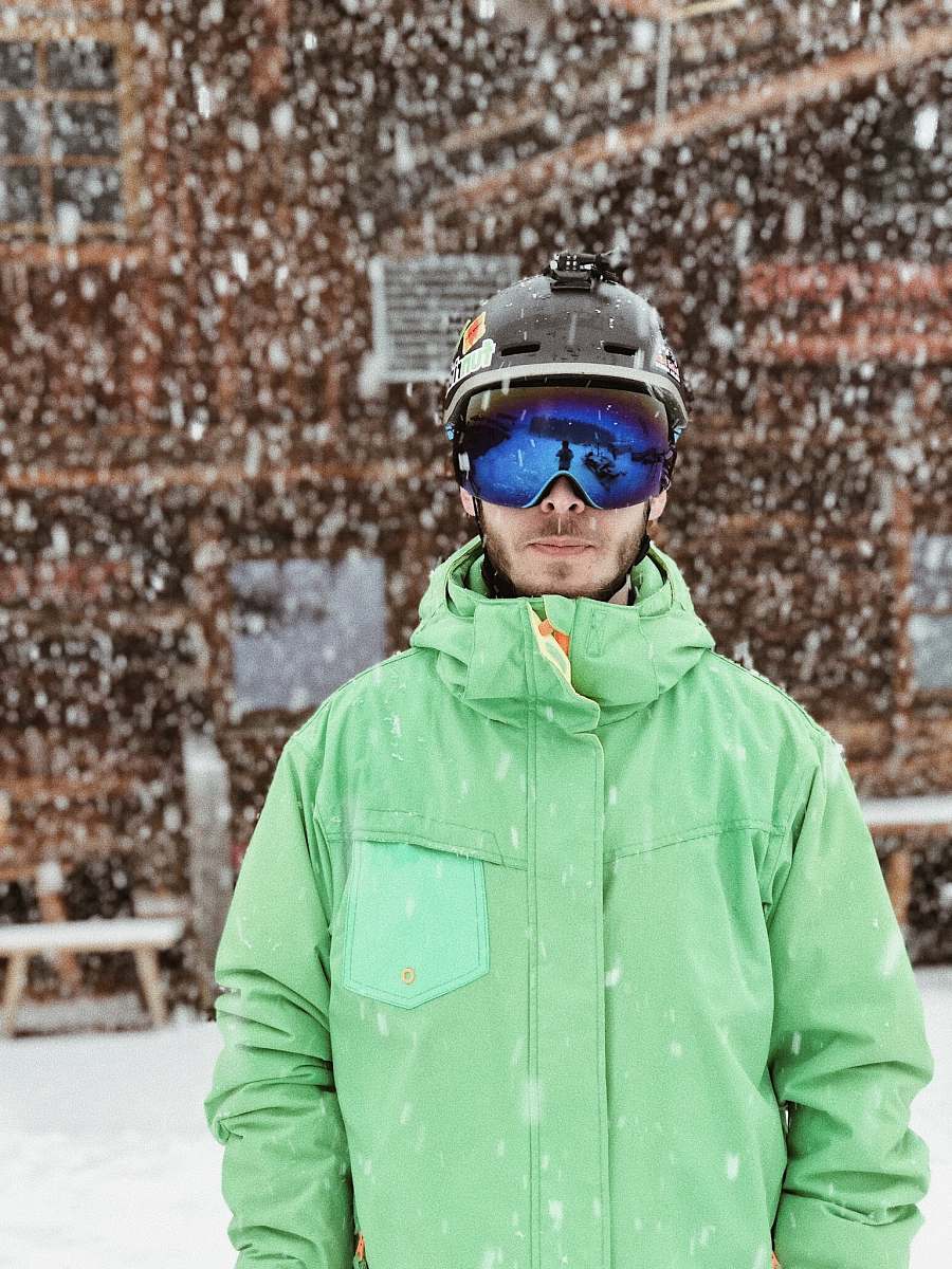 people man in green zip-up hooded jacket black helmet and black goggles standing on snow during daytime person