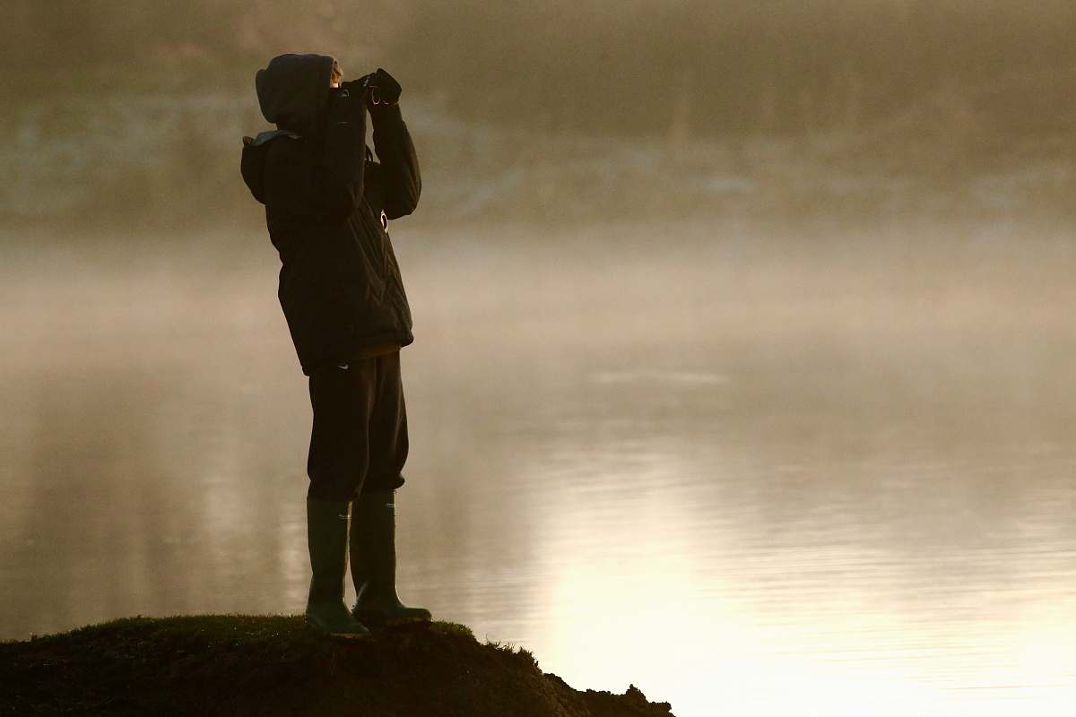 people man on cliff looking at binoculars person