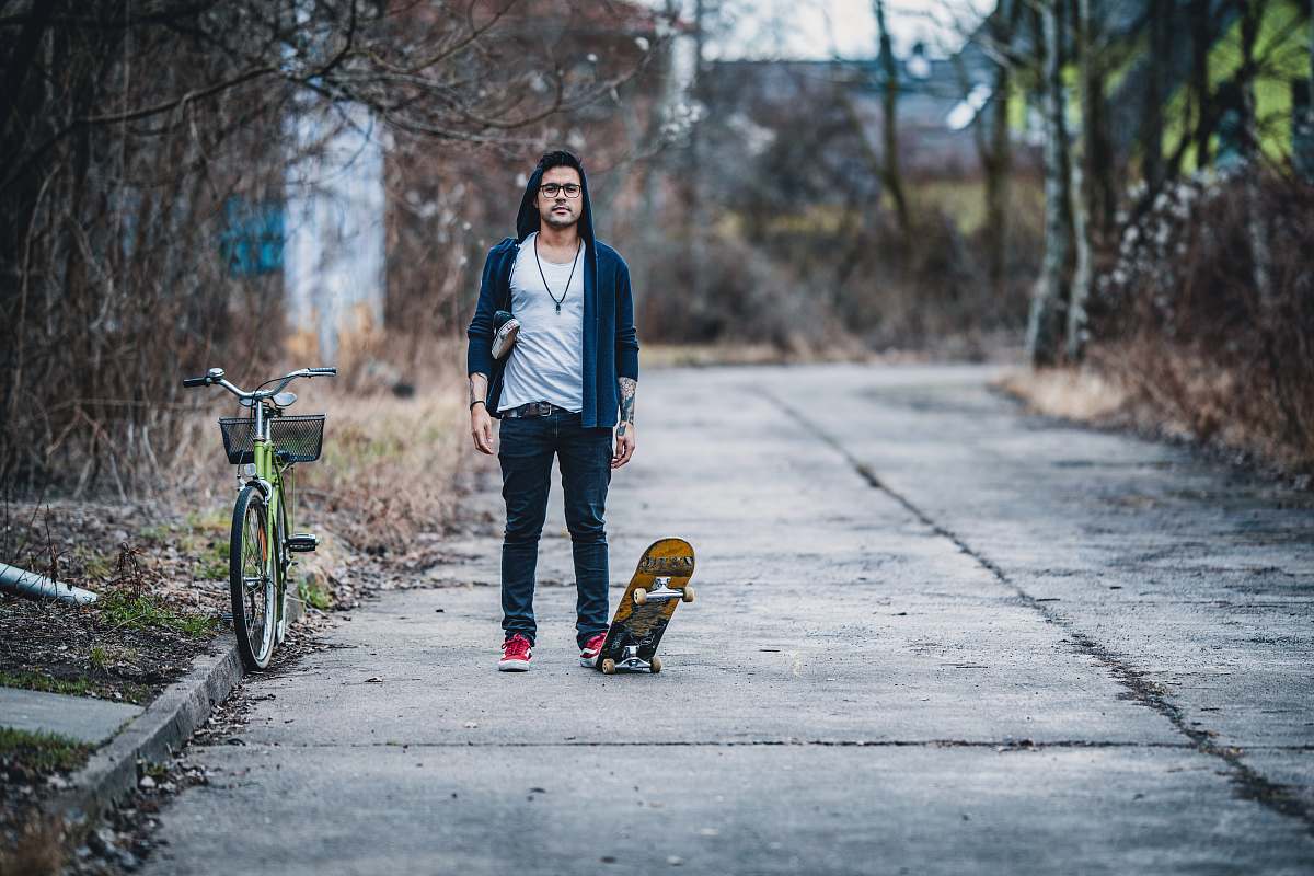 bicycle man playing a skateboard beside green city bicycle bike