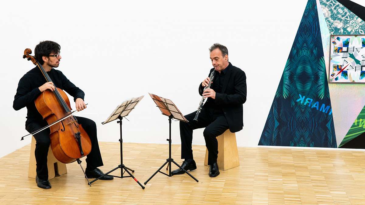 person man playing flute near man playing cello people