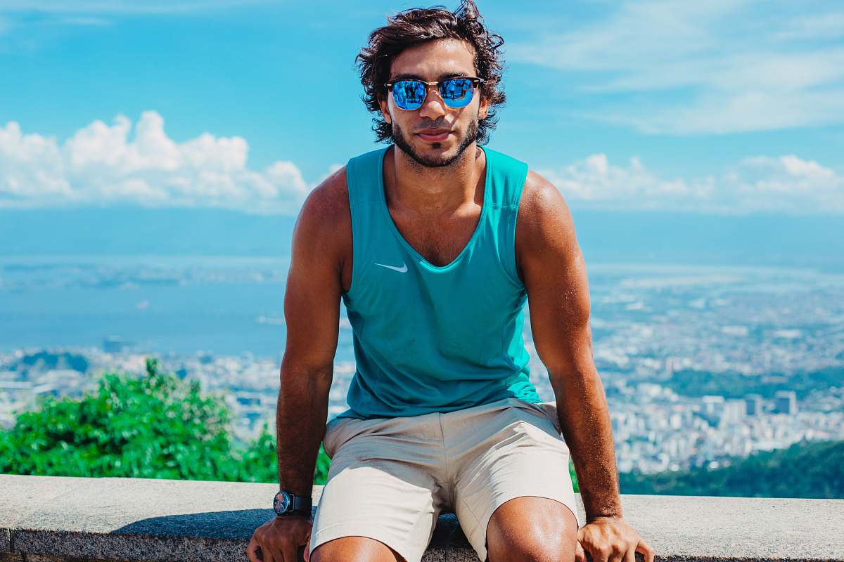 person man sitting on grey concrete bench with overview of city on background during daytime people
