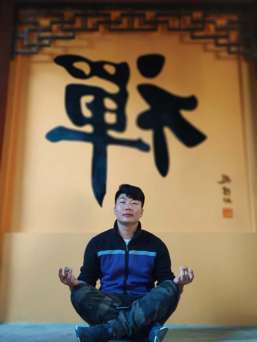 people man sitting with his legs crossed in front of yellow wall person