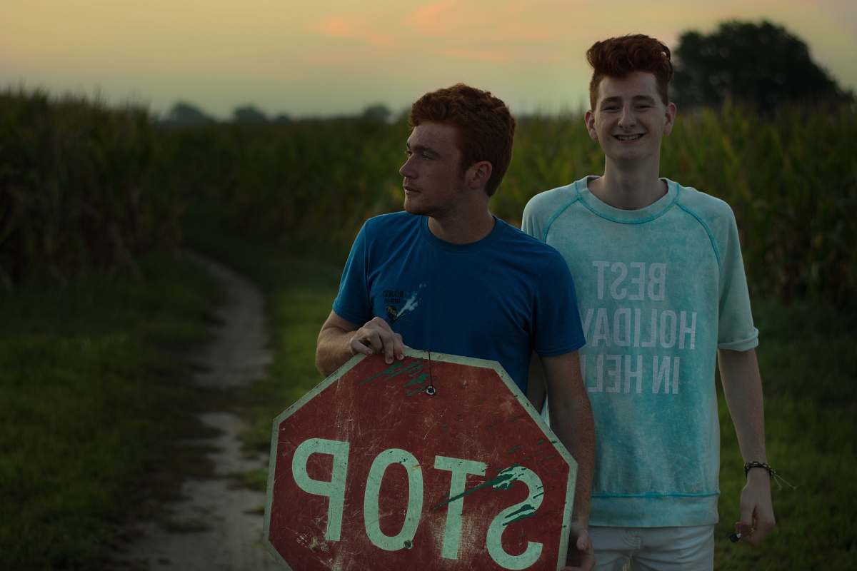people man standing beside man holding stop signage near green grasses during daytime person