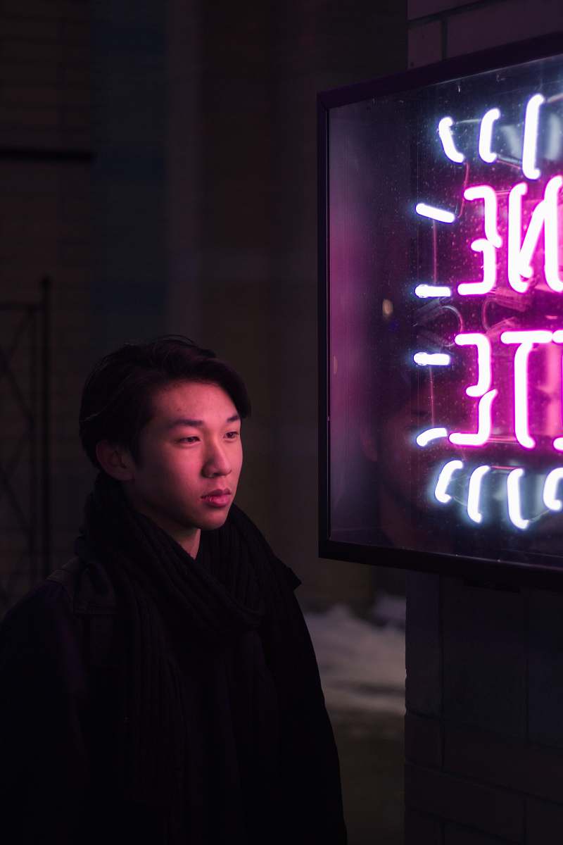 people man standing beside pink and blue neon light signage person