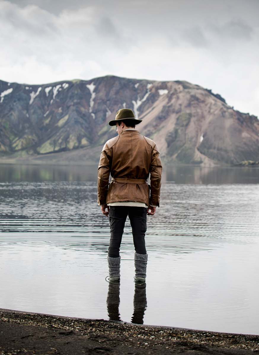 people man standing in body of water facing toward mountain person