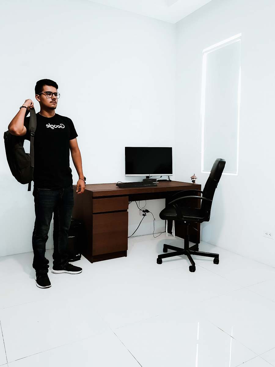 person man standing near brown desk beside white wall people