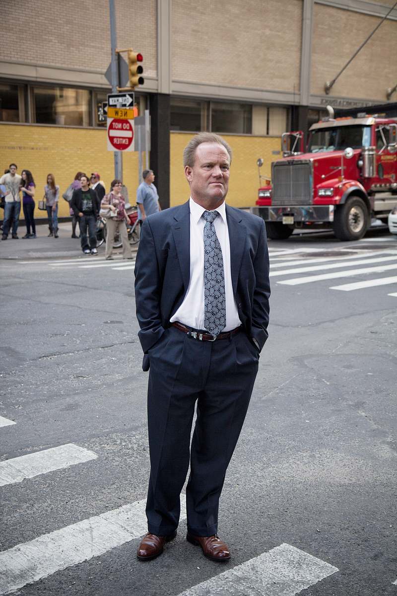people man standing near road next to people during daytime suit