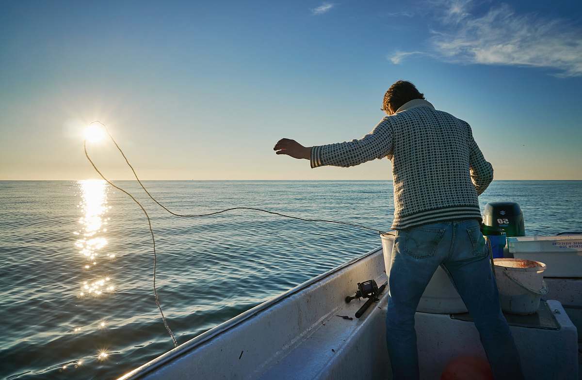 person man standing on boat throwing rope on water boat