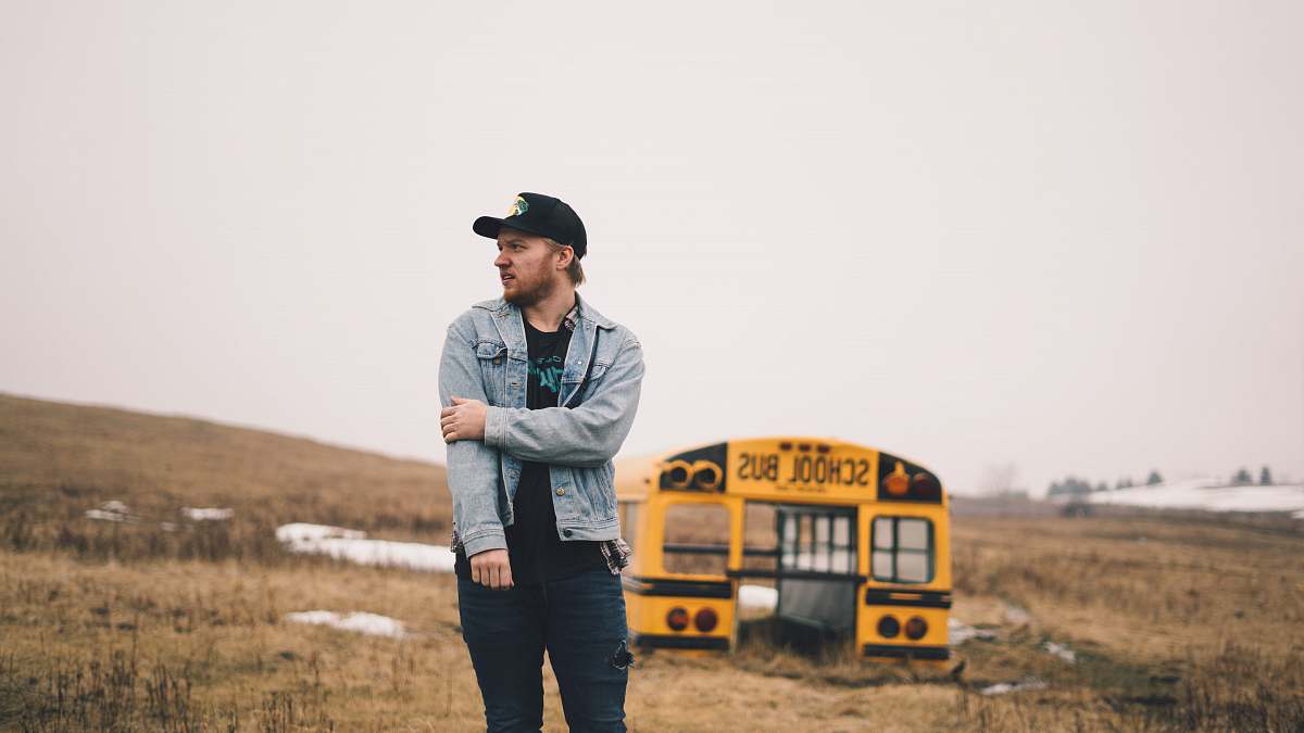 people man standing on grass field near school bus part during daytime bus