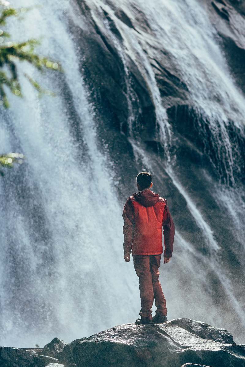people man standing on rock facing waterfall nature