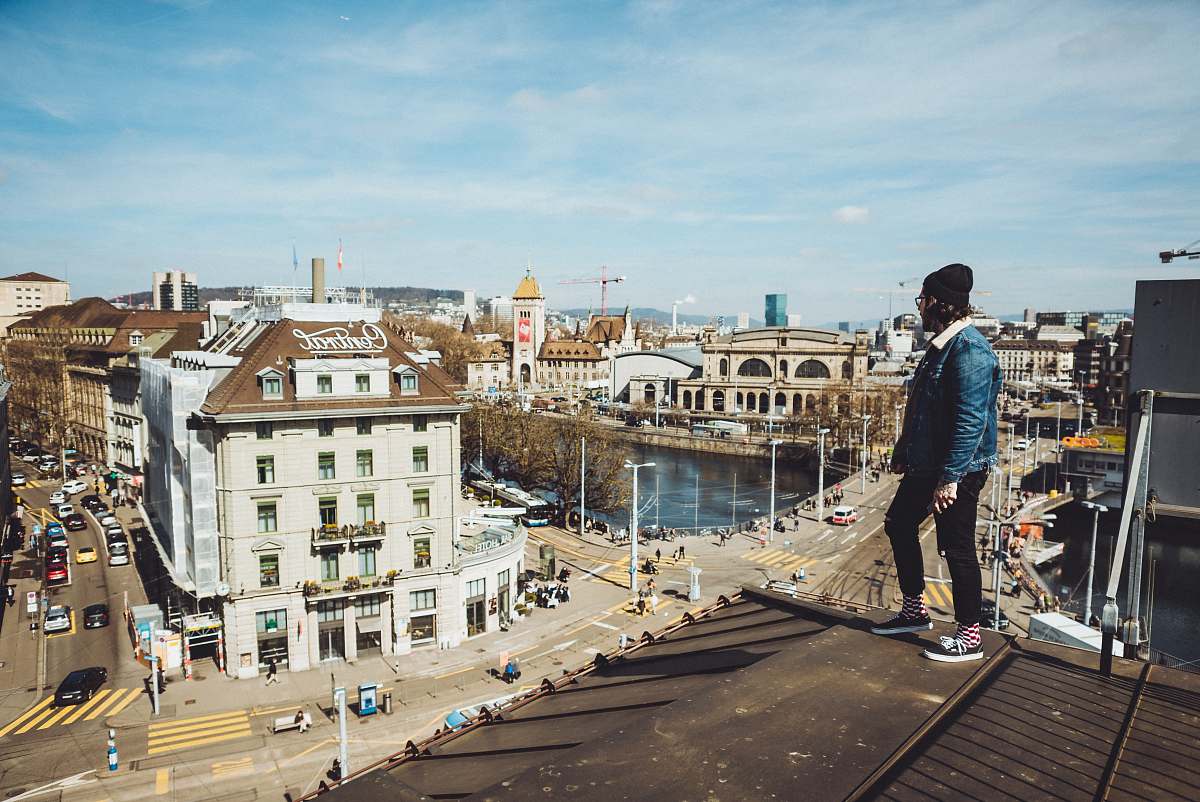people man standing on roof near buildings during daytime person