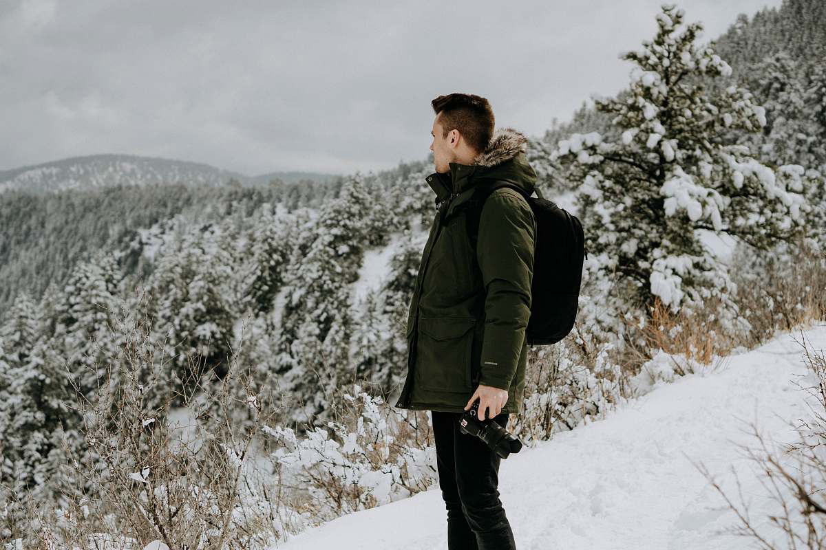 people man standing on snow-covered land during daytime person