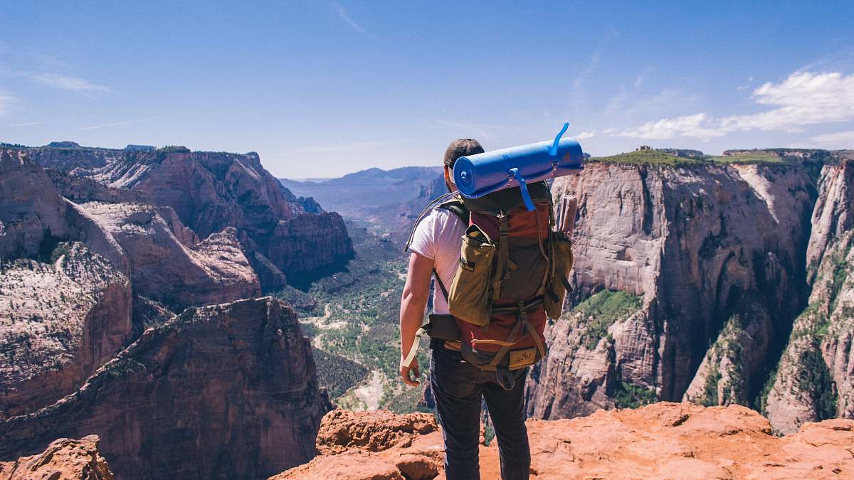 people man standing on top of mountain facing mountain view person