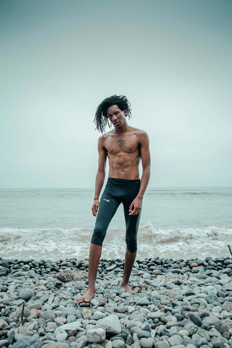 person man standing wearing black Nike shorts near the beach people