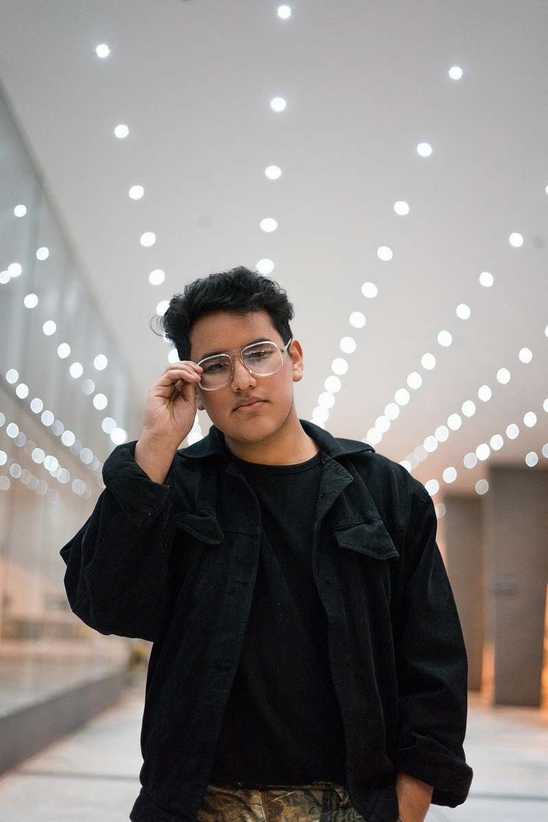 people man standing while holding his eyeglasses inside room person