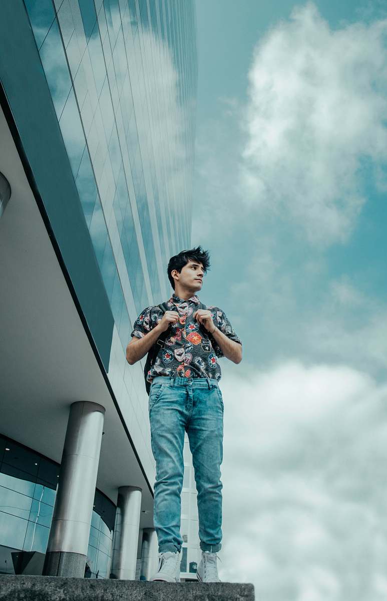 people man walking beside glass building under cloudy blue sky during daytime person