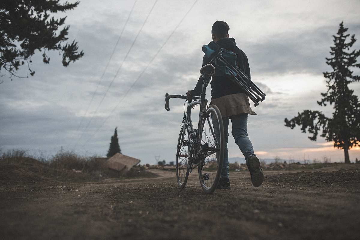 grey man walking beside road bike bike