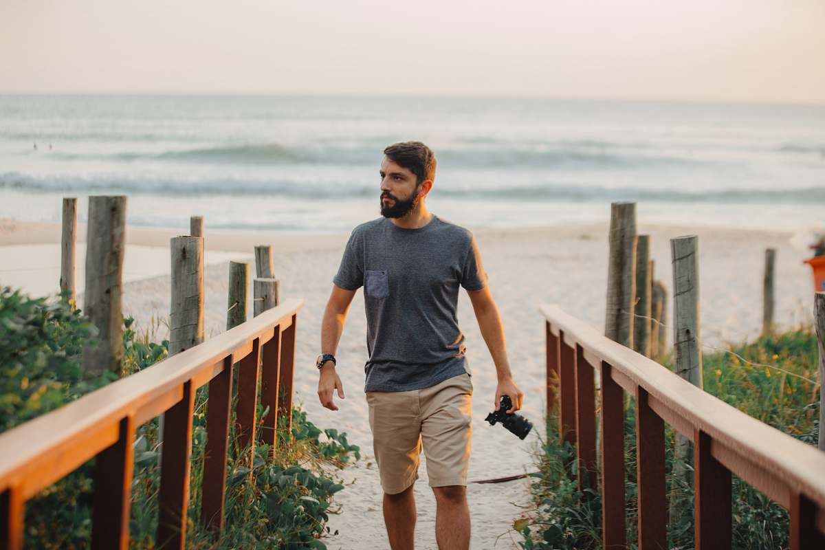 people man walking holding camera near shoreline person