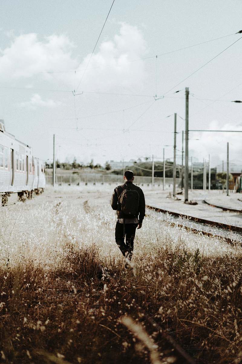 people man walking into grass field during daytime person