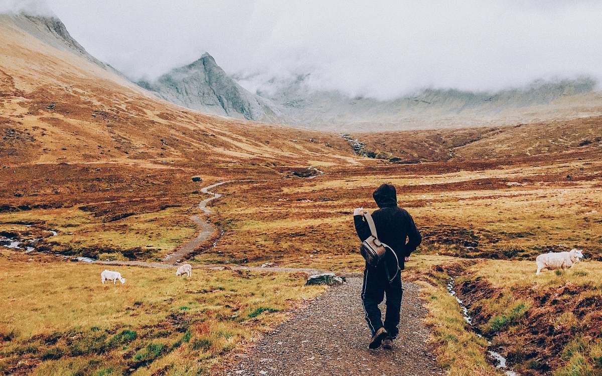 person man walking on road towards mountain mountains