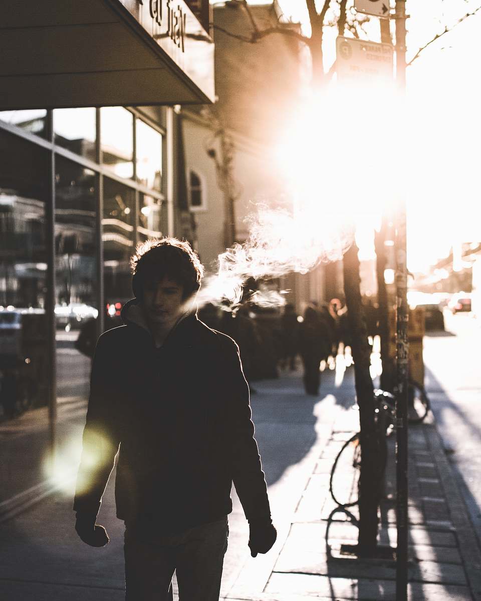 people man walking on sidewalk beside glass wall person