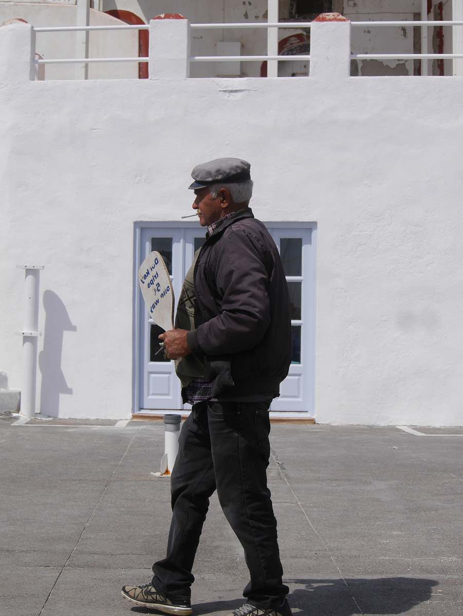 people man walking while holding brown sign near white concrete building person