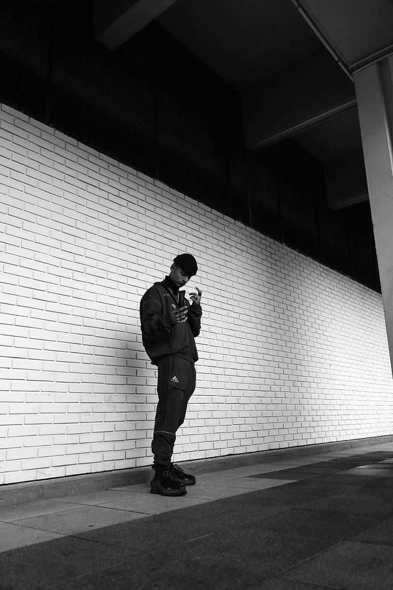 people man wearing black adidas pants s tanding on concrete floor black-and-white
