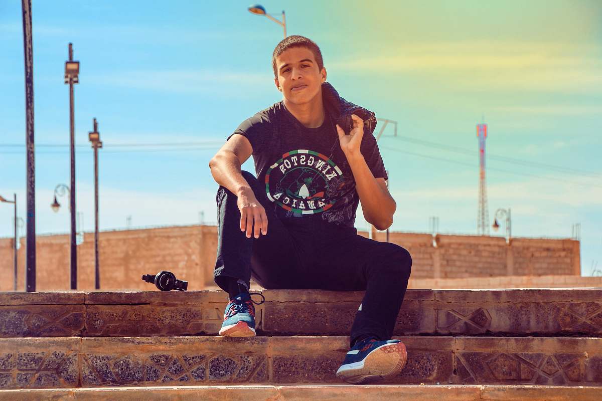 people man wearing black Kingston t-shirt sitting on stair while holding hoodie person