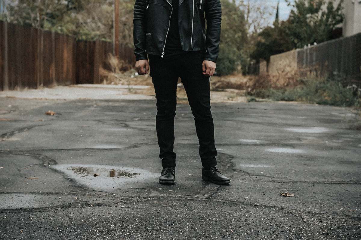 people man wearing black pants standing on gray road person