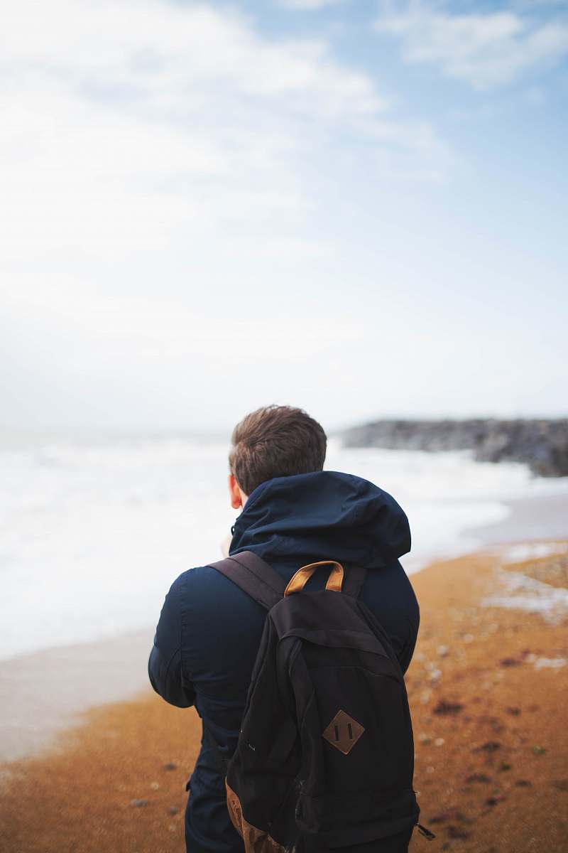 people man wearing blue hooded jacket standing near the sea person