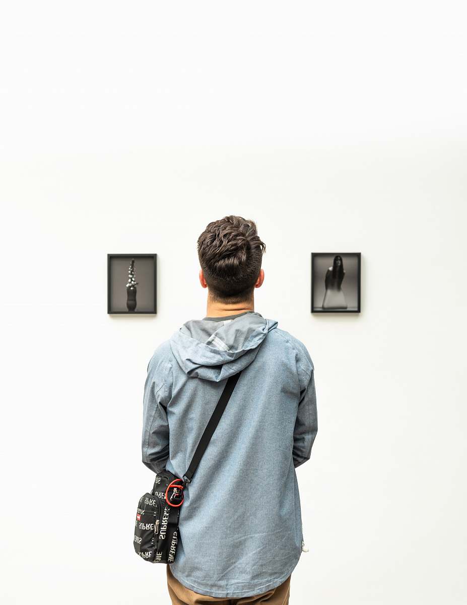 people man wearing hoodie looking at artworks person