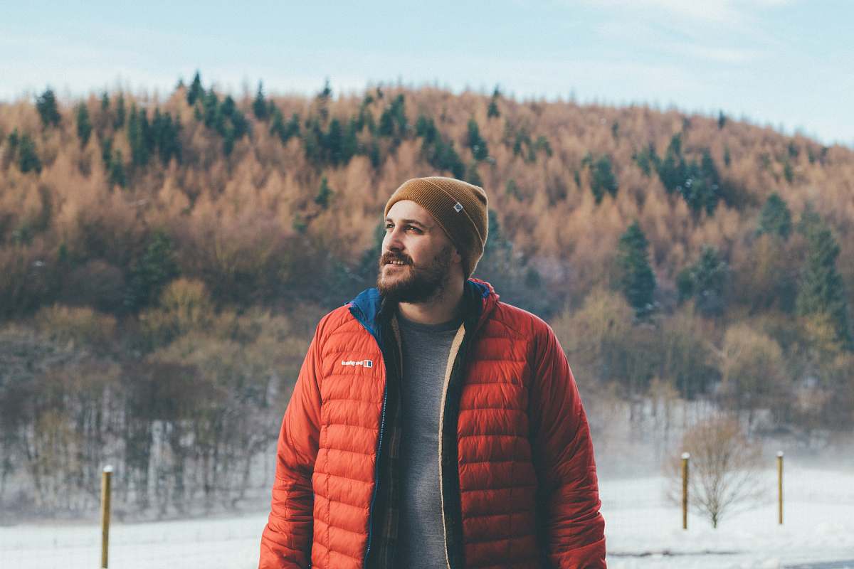 people man wearing orange bubble jacket standing on snowfield staring at top-left side person