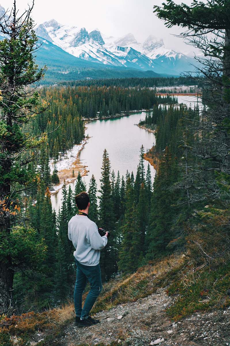 people man wearing sweater standing on cliff watching river person