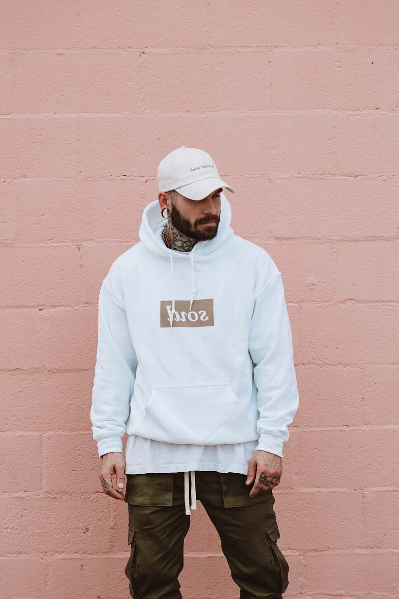 people man wearing white pullover hoodie standing against the wall person