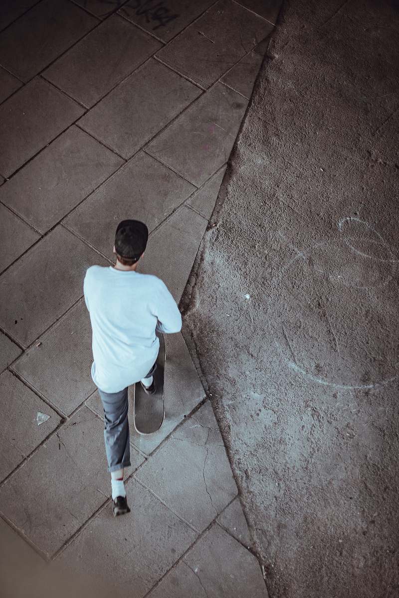 people man wearing white shirt and black cap while riding on skateboard person