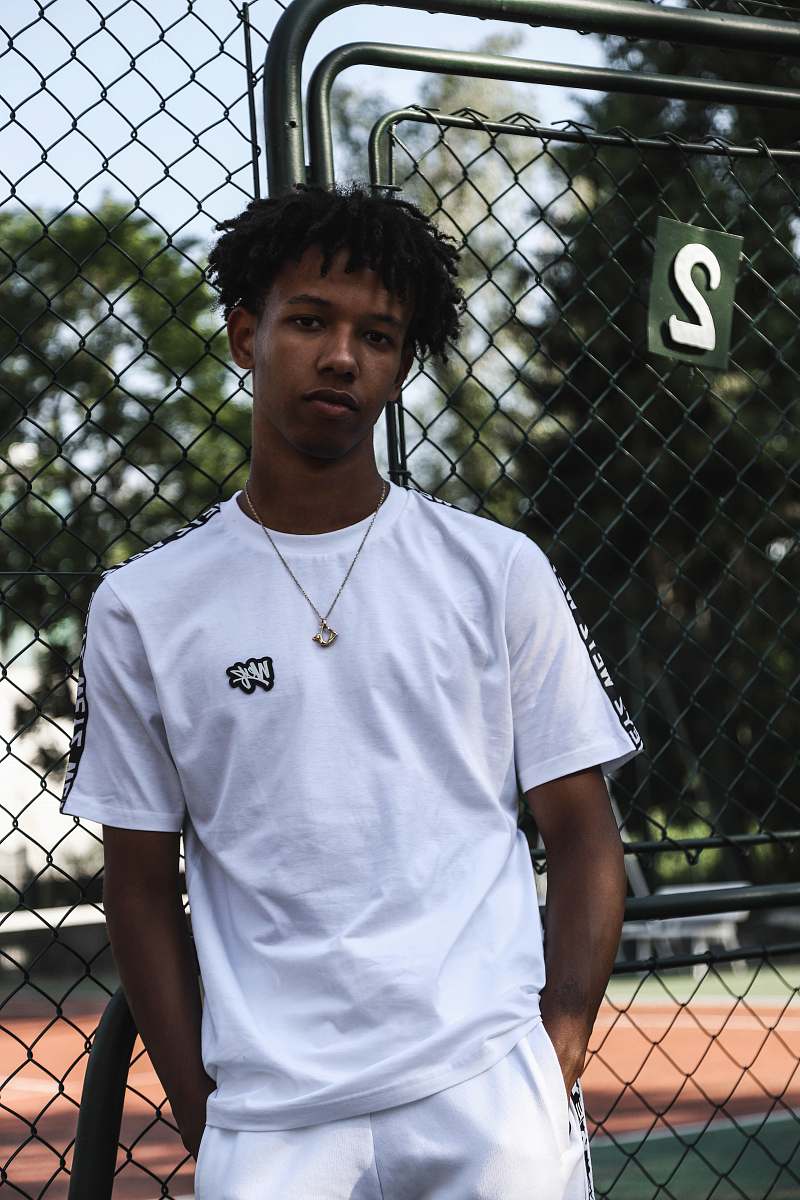people man wearing white t-shirt beside gray wire fence person