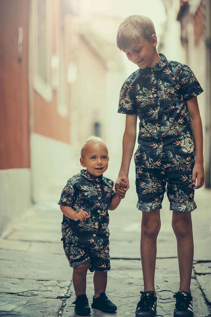 people matching pair of boy's black and gray floral collared shirt and shorts standing on gray concrete area person