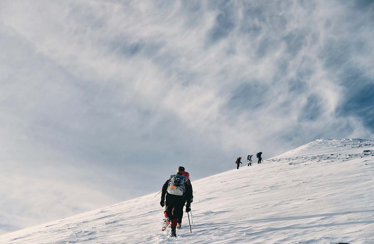 person men climbing snow covered mountain people