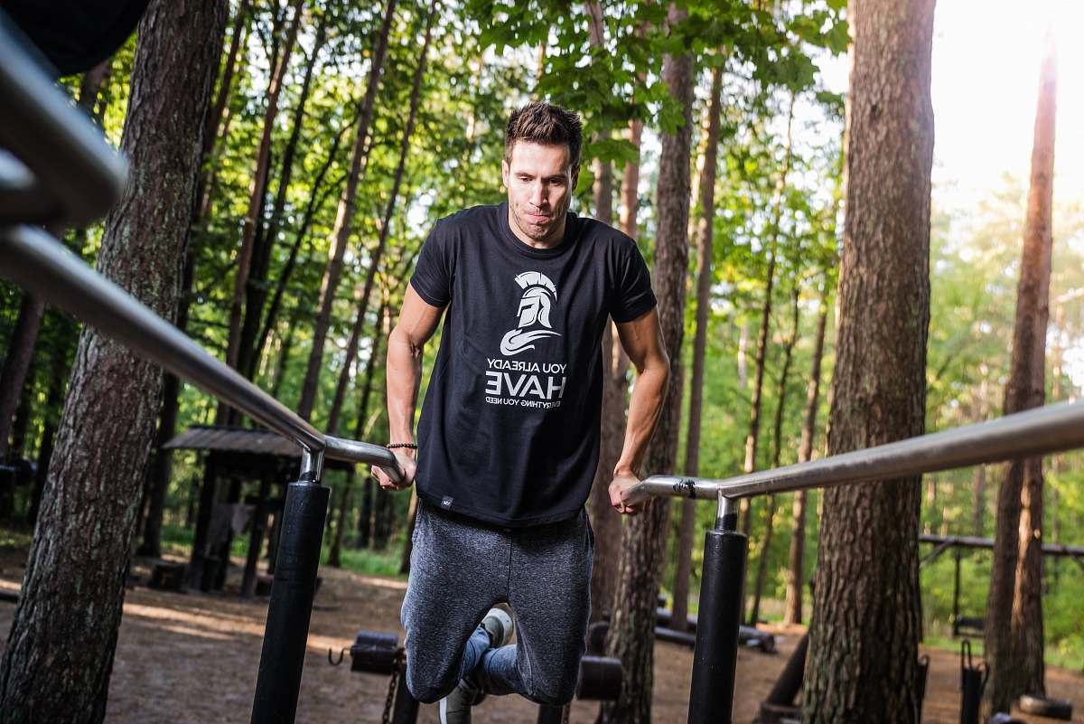 person person doing dips on gray rails under shade of trees during daytime people