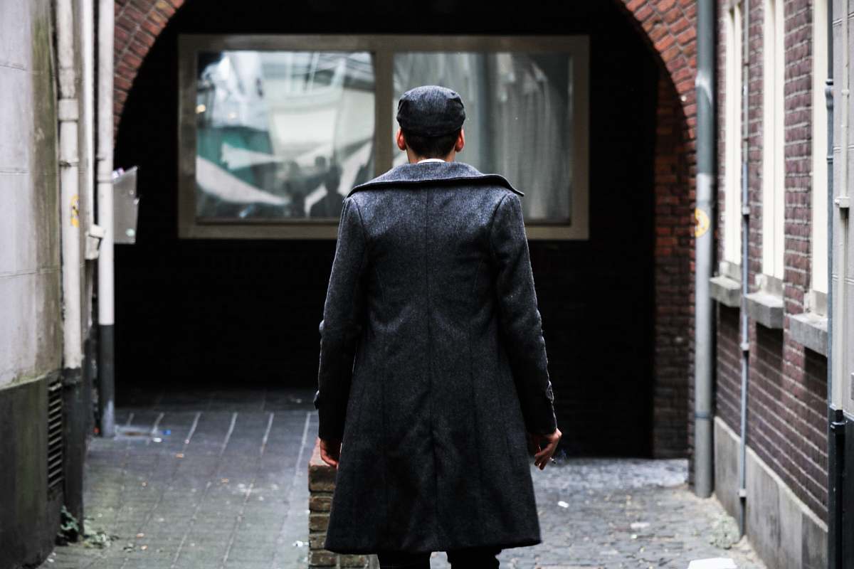 people person in black long coat standing near clear glass window person